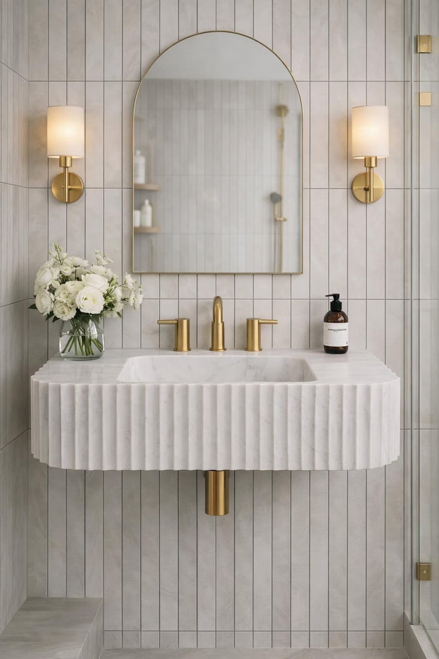 Modern bathroom with a white marble sink, gold fixtures, and decorative wall lights.